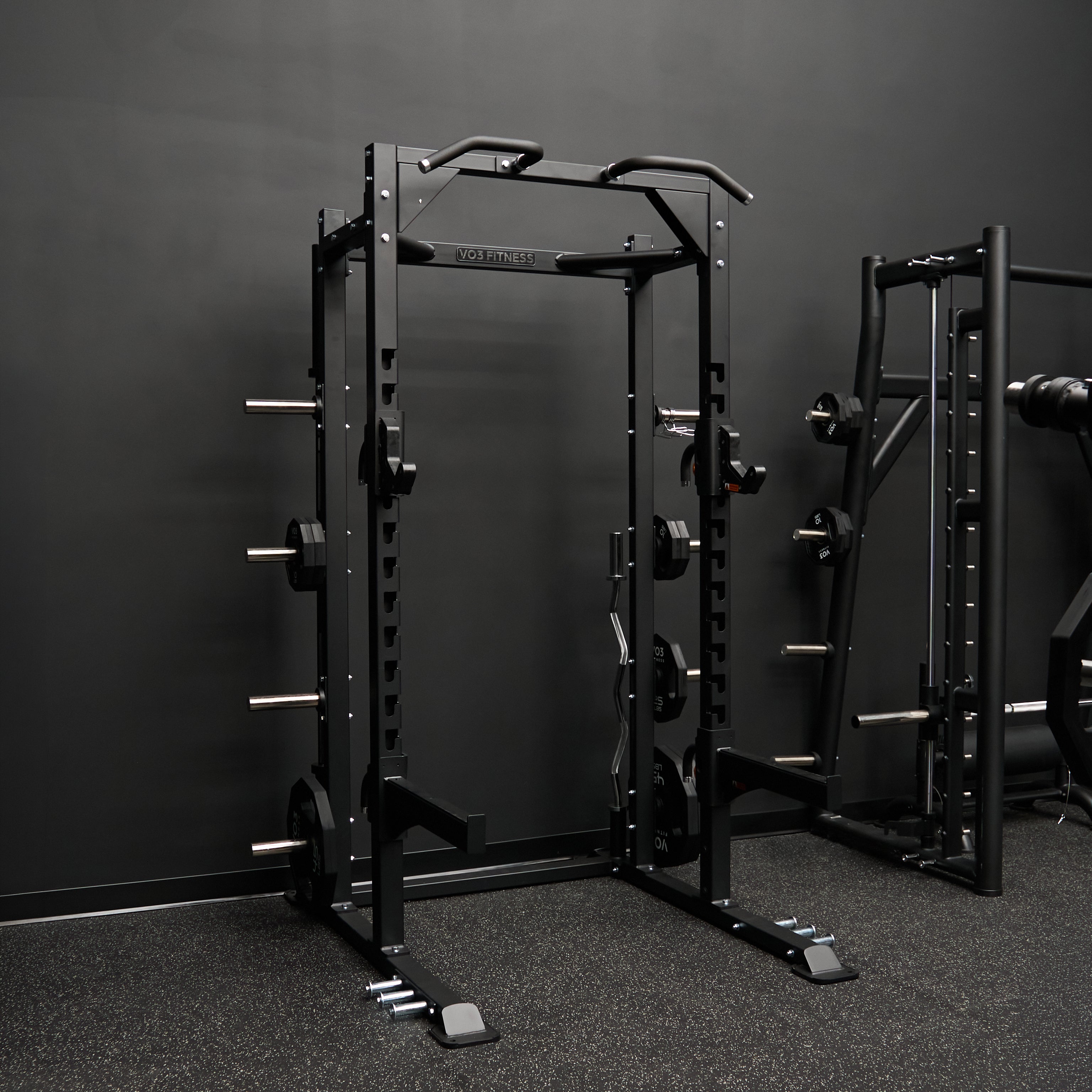 Black power rack with weight plates stored on its uprights in a home gym
